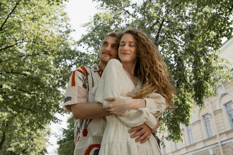  Couple s’enlaçant tendrement dans un parc ensoleillé, exprimant la confiance, la sérénité et la complicité d’une relation amoureuse épanouie.