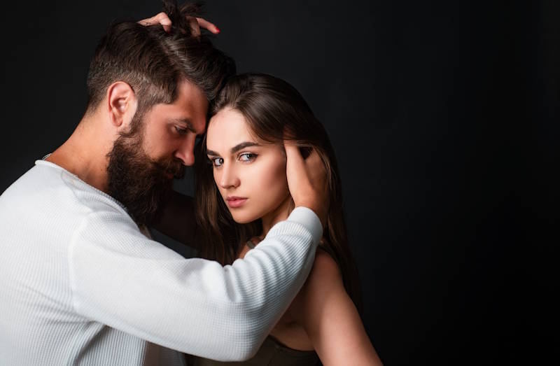 Un couple se regarde avec intensité, entre amour et méfiance, illustrant la jalousie et la peur de perdre l’autre.
