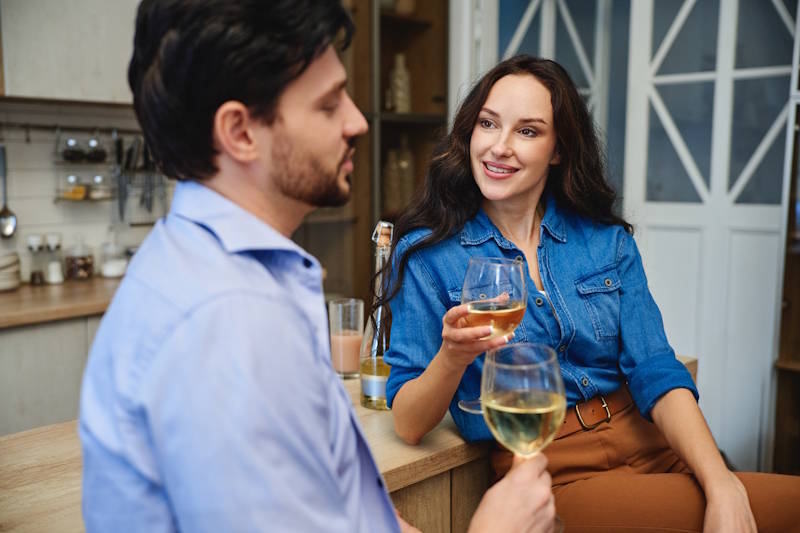 Couple discutant calmement autour d’un verre de vin, symbole d’écoute et de communication retrouvée dans la relation amoureuse